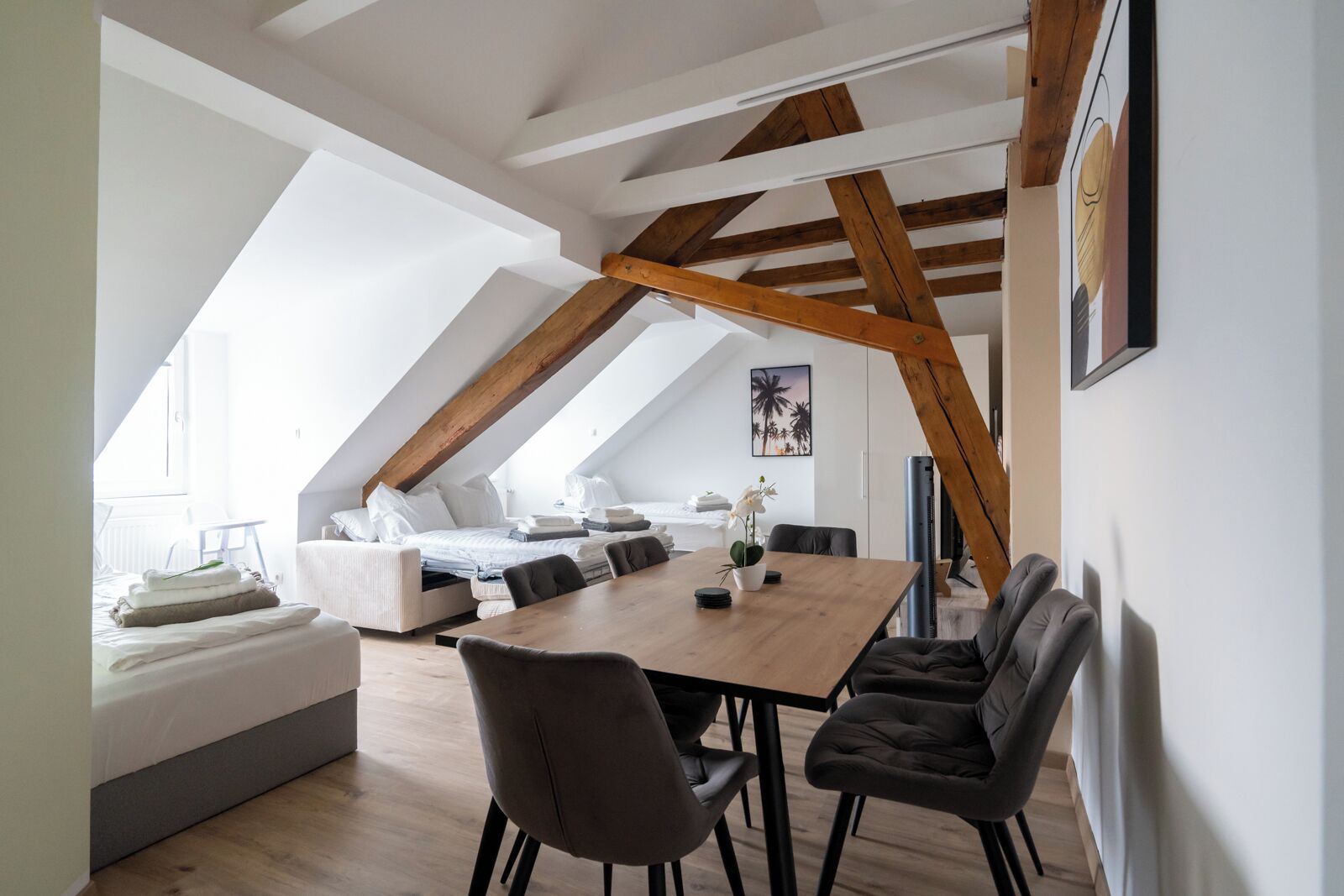Een moderne loft slaapkamer met een schuine plafond, een houten eettafel en een gezellige zithoek.