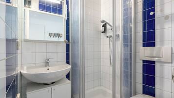 Ein modernes Badezimmer mit einem weißen Waschbecken, einer Duschkabine und blauen Fliesenwänden.
