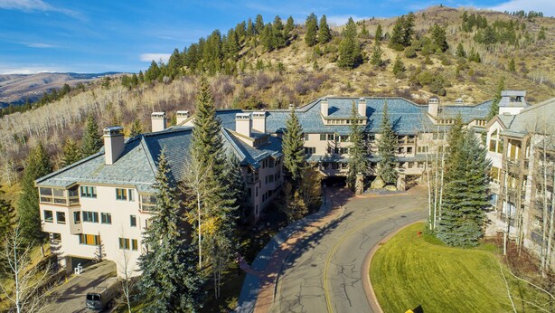 A large, multi-story hotel with a central courtyard, surrounded by trees and hills. - Beautiful Mountain Residence, Ski in/out, Year-Round Pool and Hot Tubs (Beaver Creek)