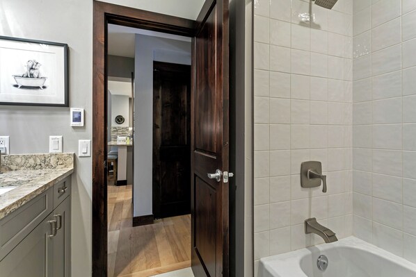 A modern bathroom with a bathtub, a shower, and a marble countertop.