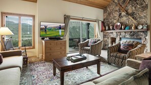 Een gezellige woonkamer met een stenen muur, een televisie en comfortabele zitplaatsen.