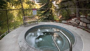 A hot tub with a metal railing, surrounded by a concrete deck and a metal fence. - Chic Streamside Home, Hot Tub, Minutes from Resort (Avon)