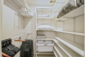 Een bergkast met planken, een kledingroede en een wasmand.