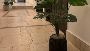 A hallway with a potted plant, a door, and a tiled floor. - Cairo casa inn (Cairo)