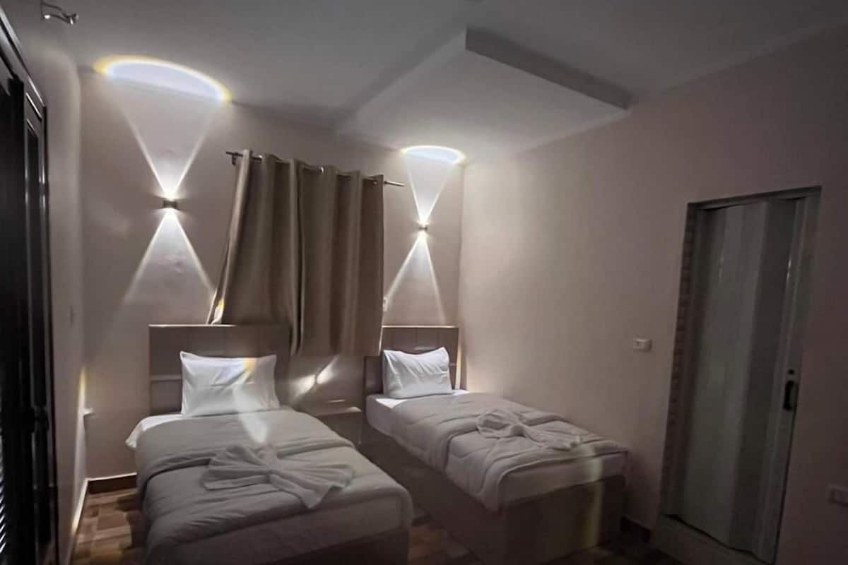 Quarto de hotel com duas camas, um espelho grande e um guarda-roupa.
