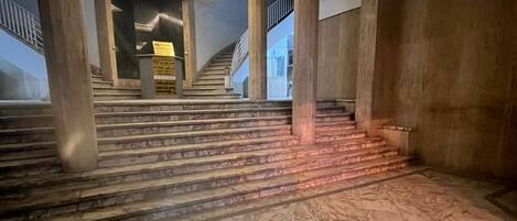 A marble-floored staircase with wooden columns and a modern ceiling design.