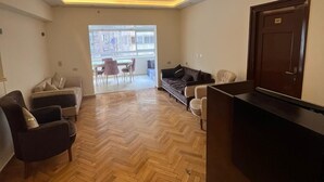 A hotel lobby with a herringbone wooden floor, a reception desk, and seating areas with sofas and armchairs. - Cairo casa inn (Cairo)