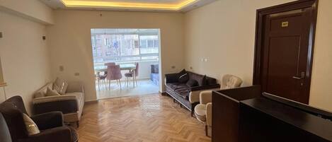Un hall de hotel con suelo de madera en dibujo de espiga, un mostrador de recepción y zonas de estar con sofás y sillones.