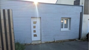Um edifício com fachada azul clara, uma porta branca com uma pequena janela e uma pequena janela lateral.
