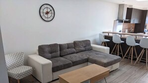 Uma sala de estar moderna com um sofá seccional, uma mesinha e uma cadeira estampada.