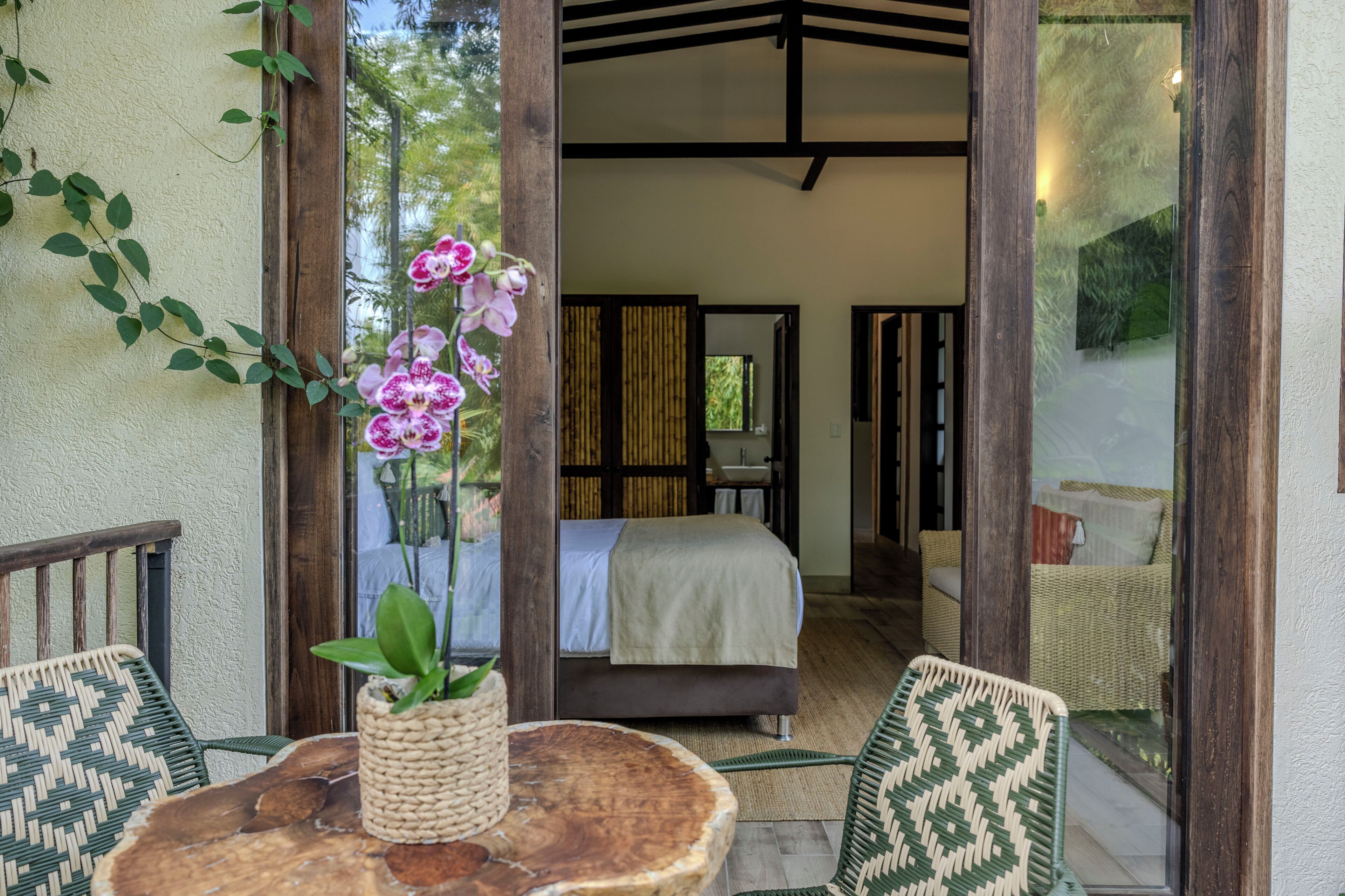 Una habitación con una cama, una mesa de fibras naturales y sillas.