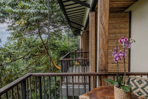 Una escalera de madera conduce a un porche cubierto con vistas a exuberante follaje.