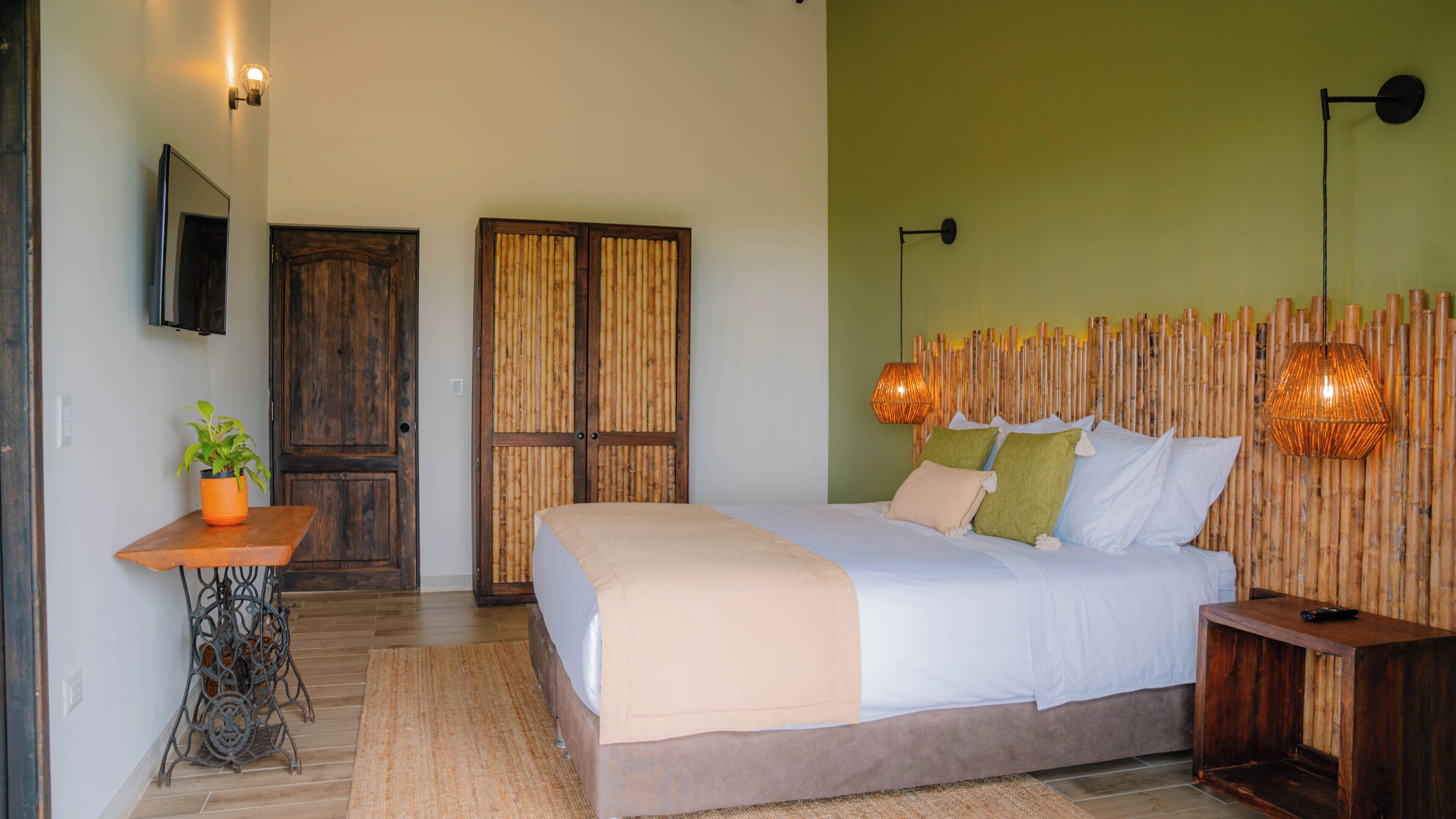 A bedroom with a bed, bedside table, and a wall-mounted TV.