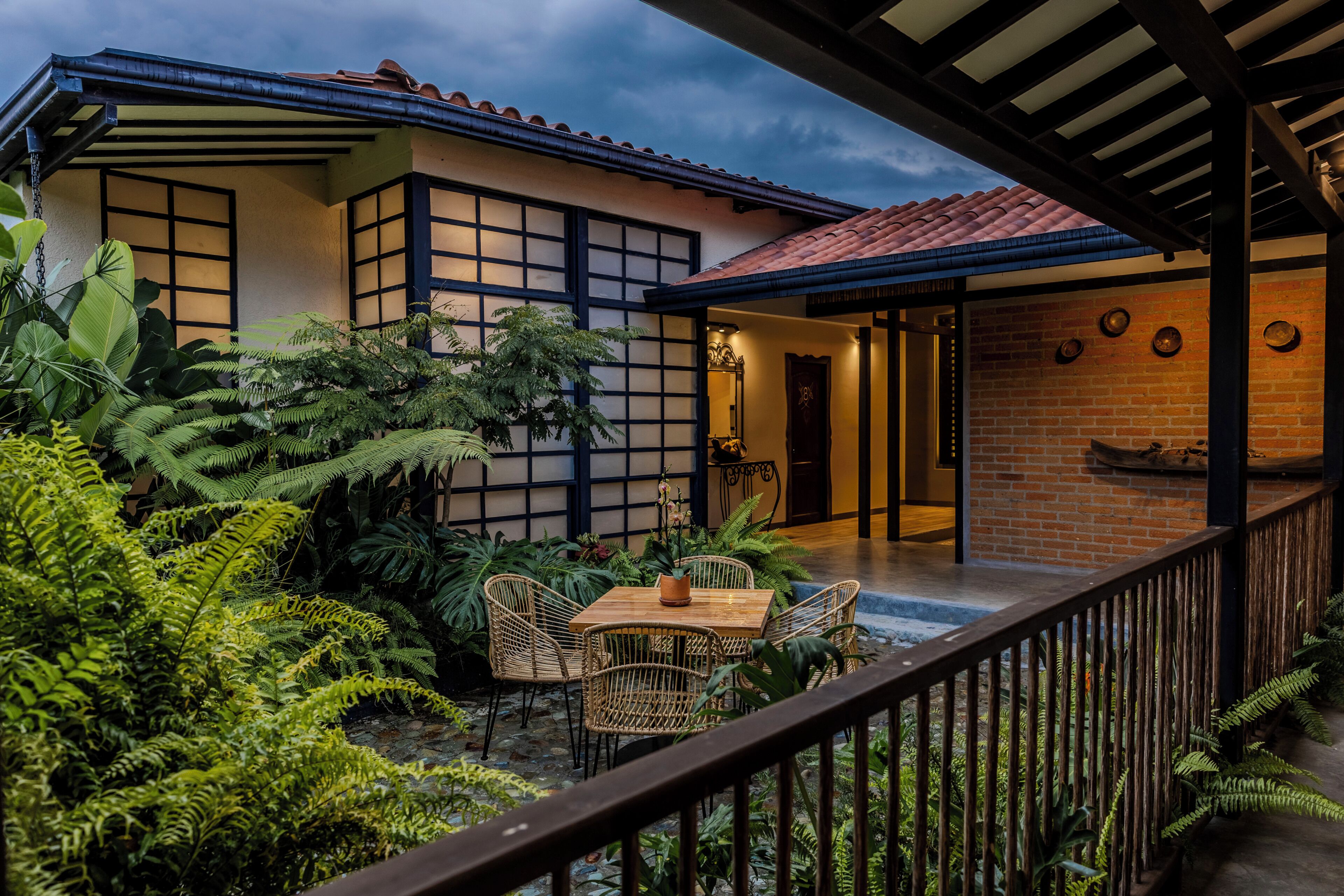 A traditional house with a covered patio, a brick wall, and a wooden table with chairs.