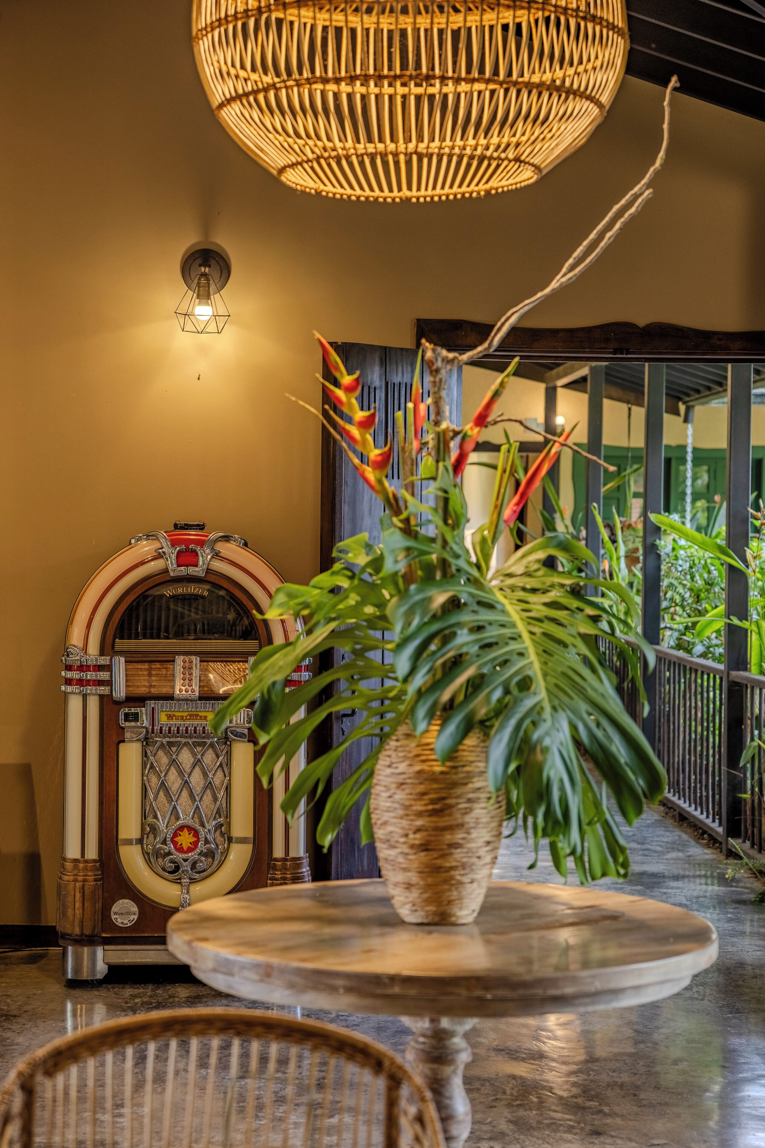 A vintage jukebox, a wicker chair, and a potted plant on a polished floor.