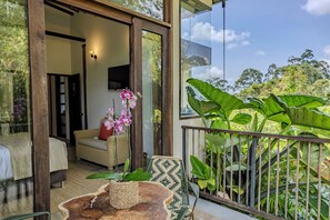 An outdoor balcony with a wicker chair, a table with a woven basket, and a potted orchid. - Tukki Ecolodge (Filandia)