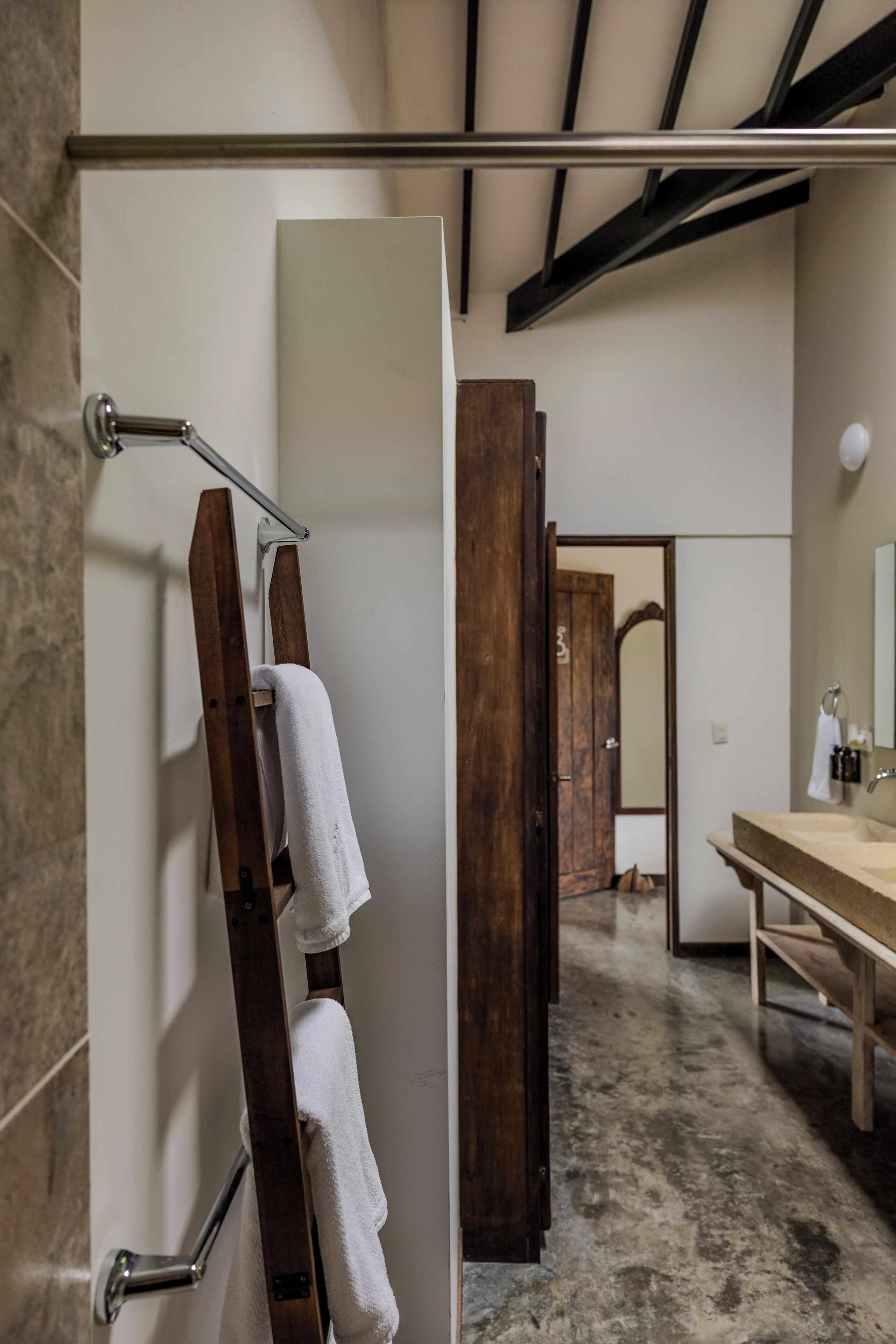 A bathroom with a wooden towel rack, a sink, and a mirror.