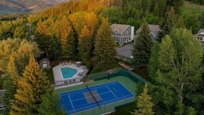 Un quartiere residenziale con campo da tennis, piscina e case circondate da alberi.