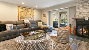 A modern living room with a leather sofa, patterned ottomans, a glass coffee table, and a fireplace. - A gem in the heart of Avon. Walk to the Lifts! (Avon)
