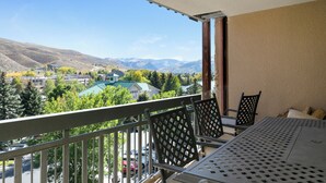 A balcony with a table and chairs, overlooking a mountainous landscape with buildings and trees. - A gem in the heart of Avon. Walk to the Lifts! (Avon)