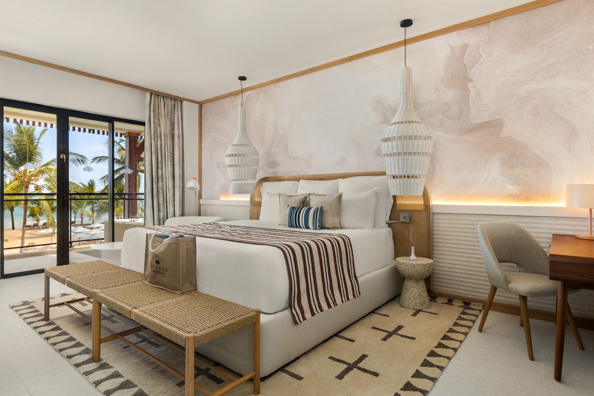A modern bedroom with a bed, bedside table, chair, and a view of palm trees.