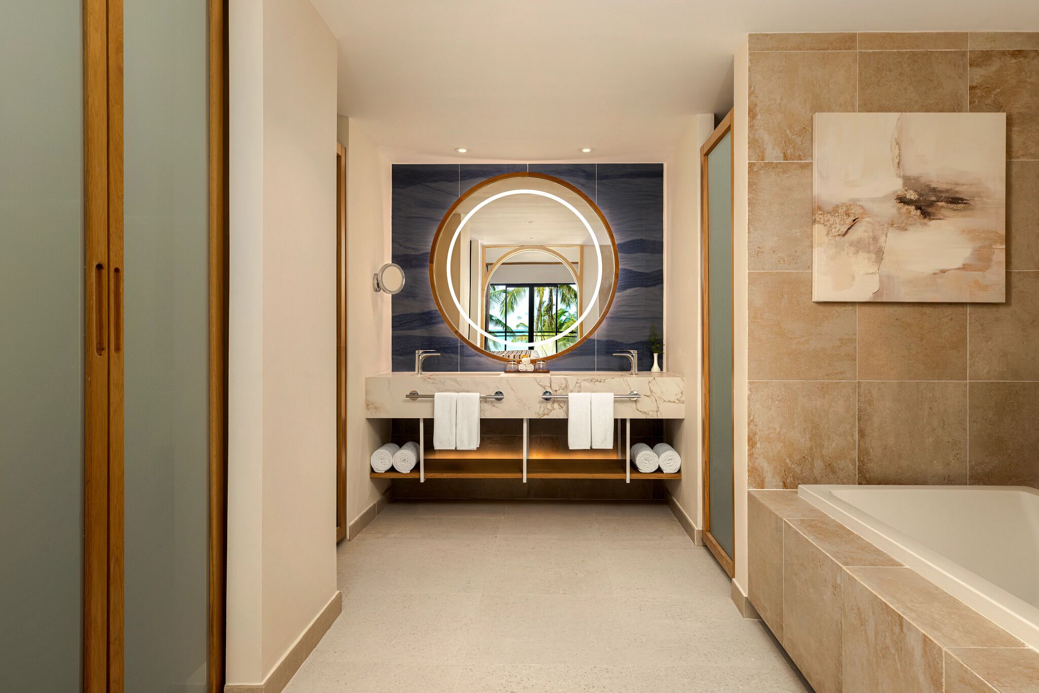 A modern bathroom with a double vanity, a large mirror, and a bathtub.