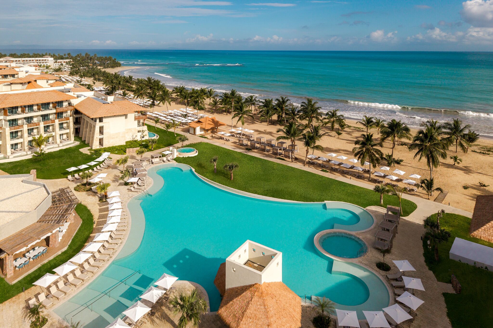 A resort with a large pool, beach, and ocean view.