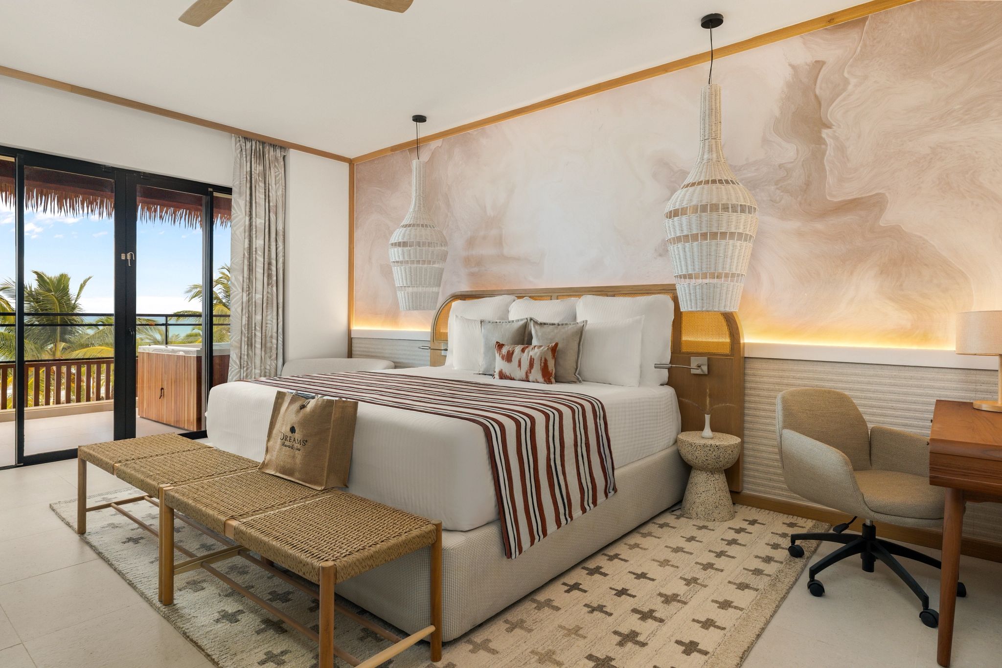 A spacious bedroom with a large bed, a desk, a chair, and a balcony with a view.