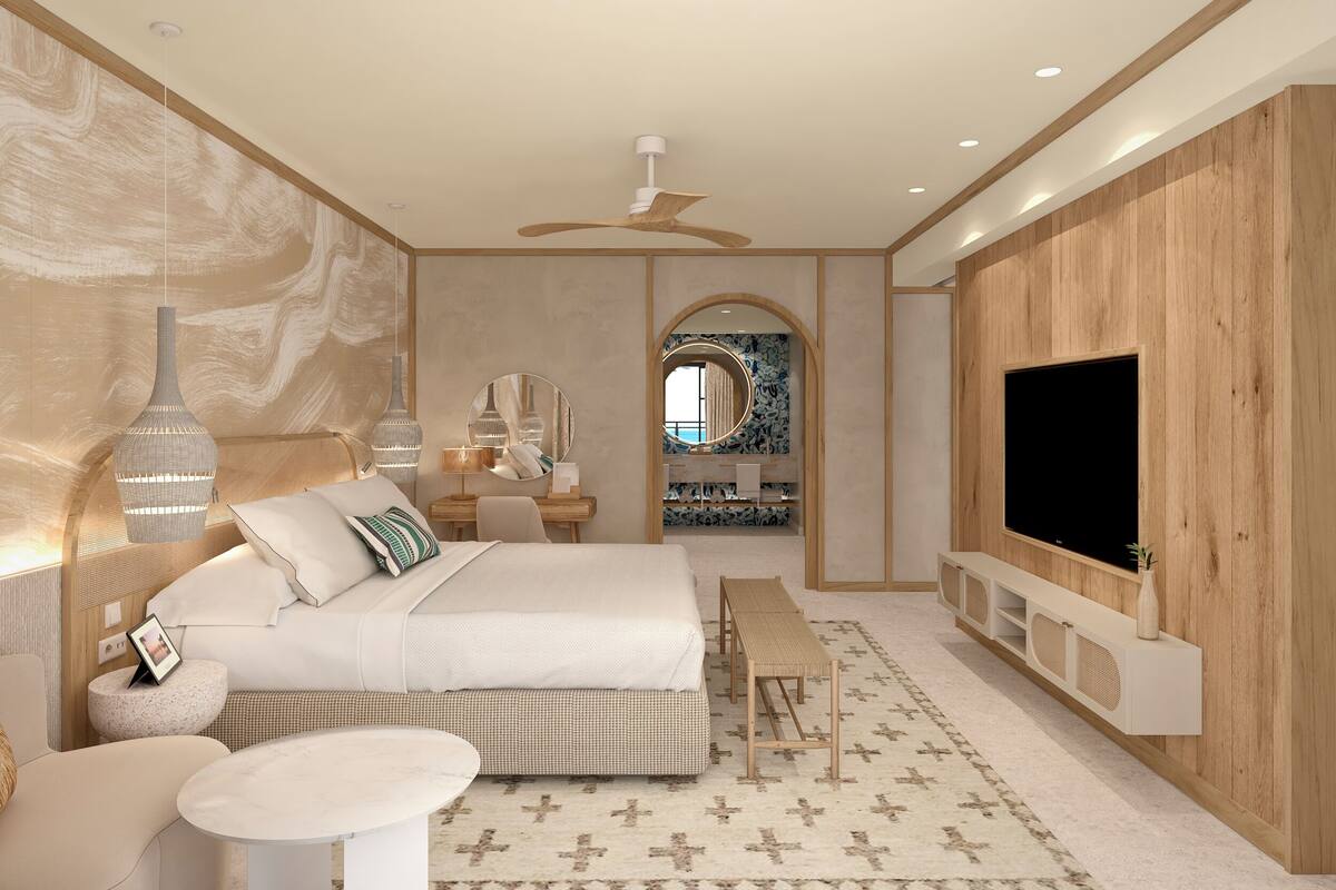 A modern bedroom with a large bed, bedside tables, a TV, and a vanity with a mirror.