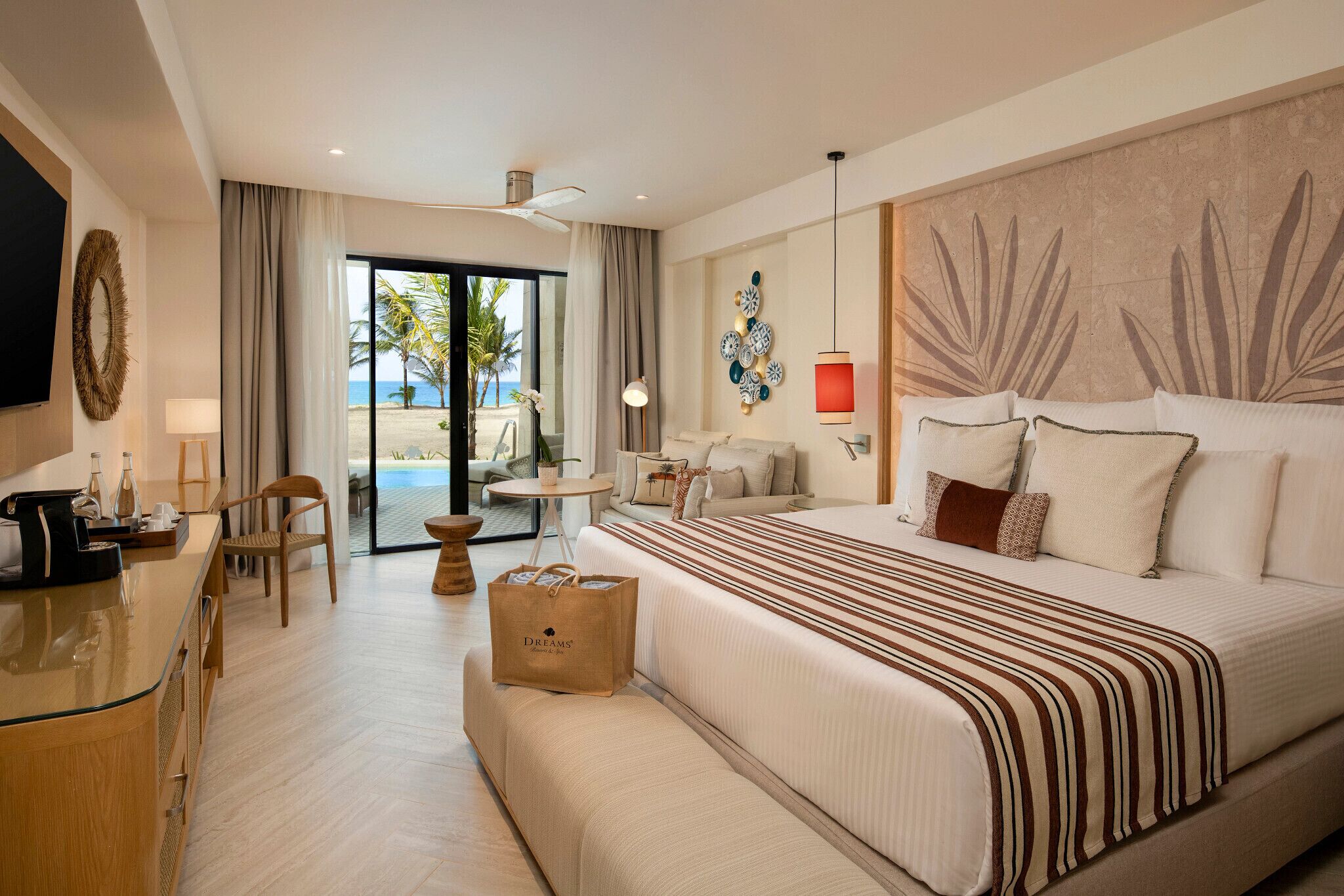 Una habitació d'hotel amb un llit gran, un escriptori, una cadira, una taula petita i vistes a la platja.