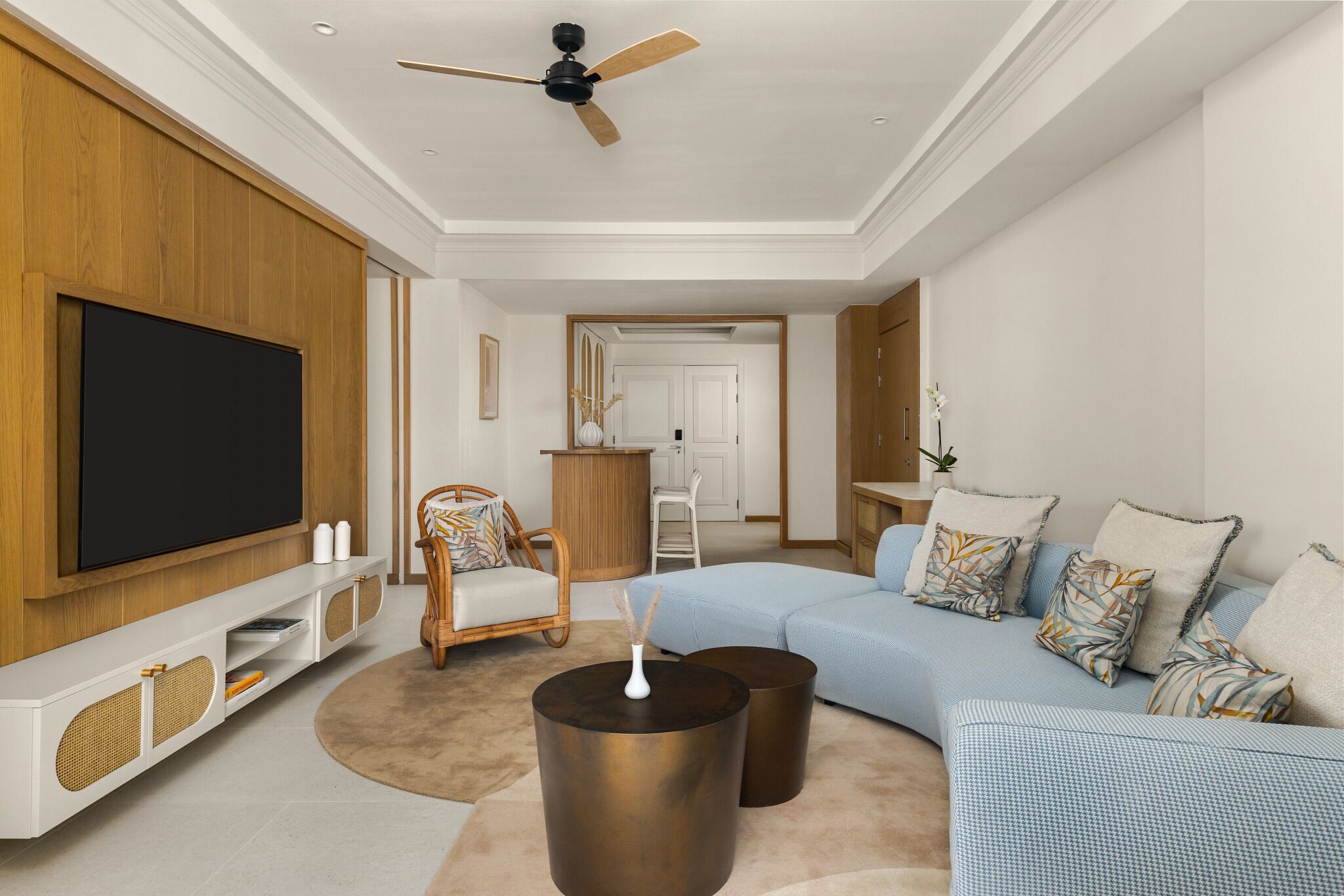 Un salon moderne doté d’un téléviseur à écran plat, d’un ventilateur de plafond, d’un ensemble de canapés et d’une table basse.