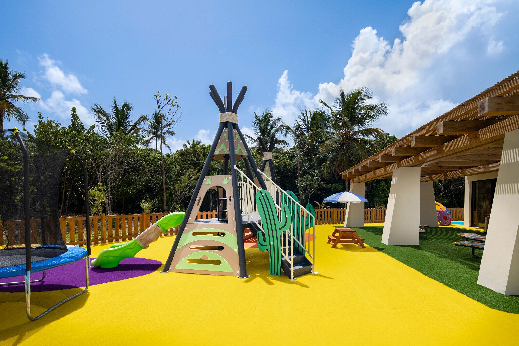 A playground with a slide, climbing structures, and a trampoline.