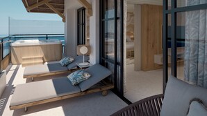 Un balcón con dos sillones de descanso, una mesita y un jacuzzi.