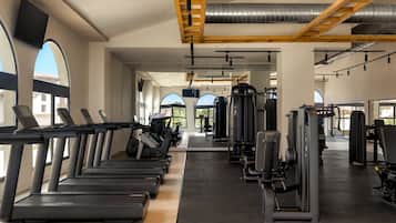 A gym with treadmills, weight machines, and a ceiling with exposed beams and ductwork.
