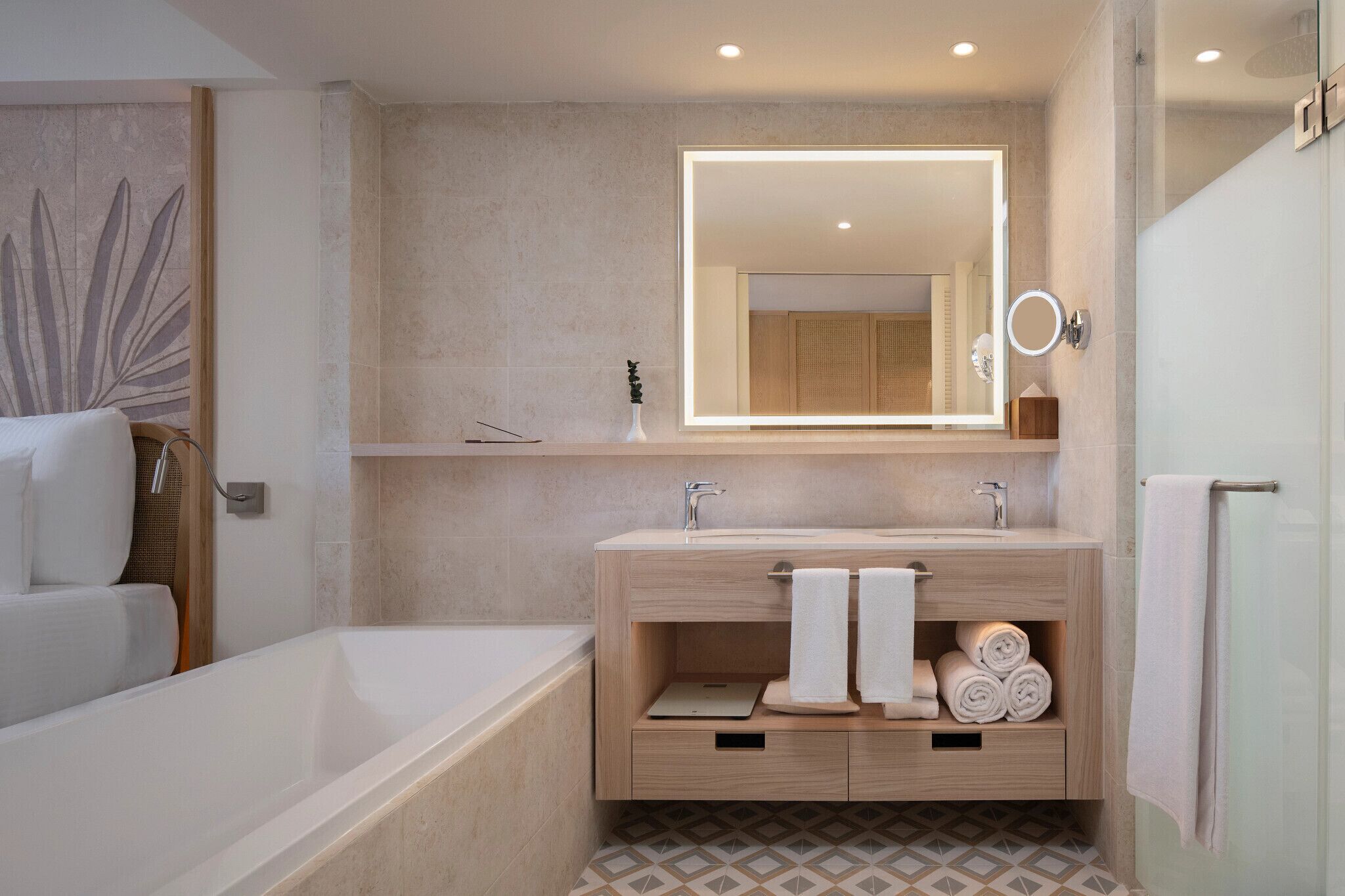 A modern bathroom with a bathtub, two sinks, a vanity with storage, a large mirror, and a shower area.