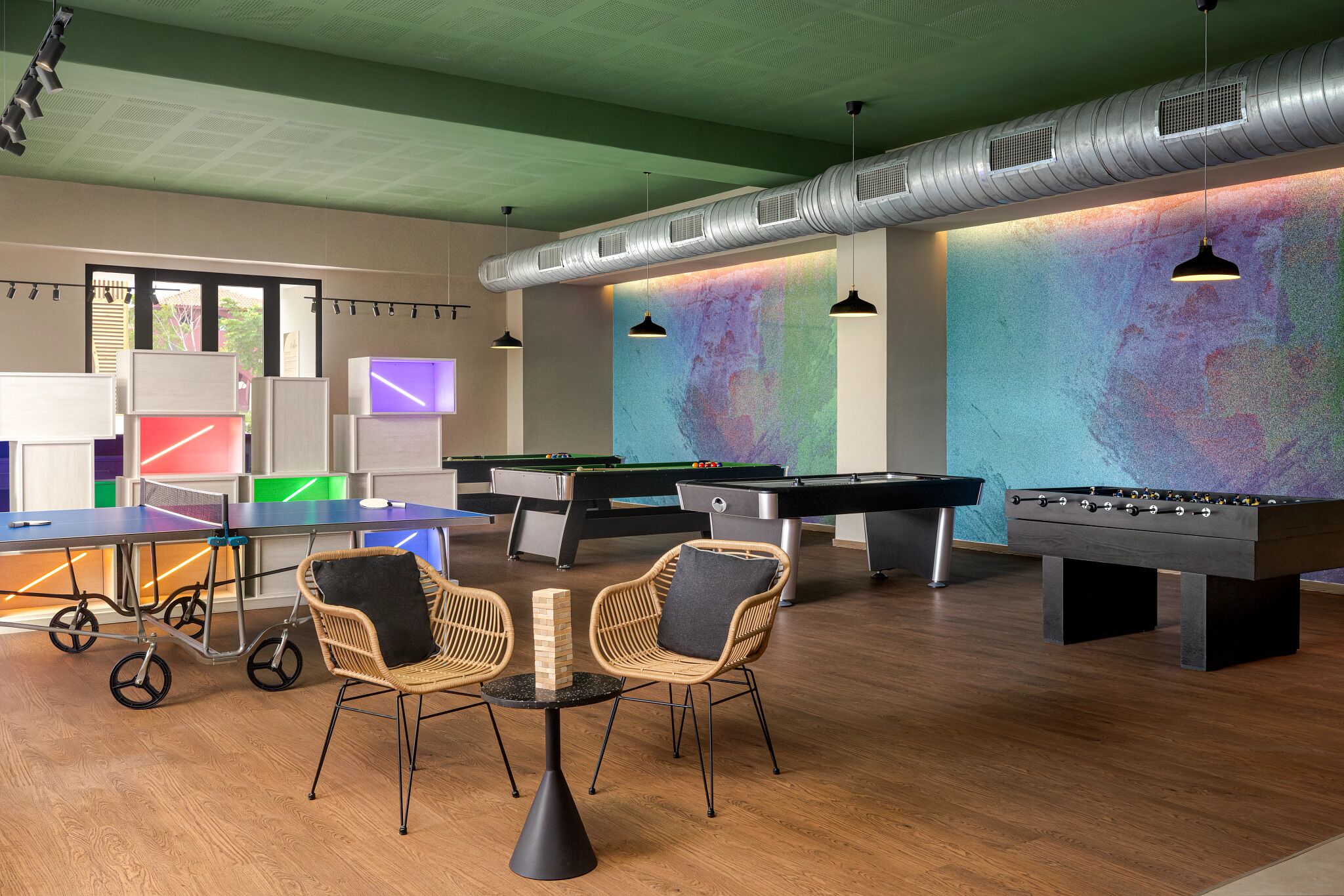 A recreation room with pool tables, foosball tables, and a ping pong table.