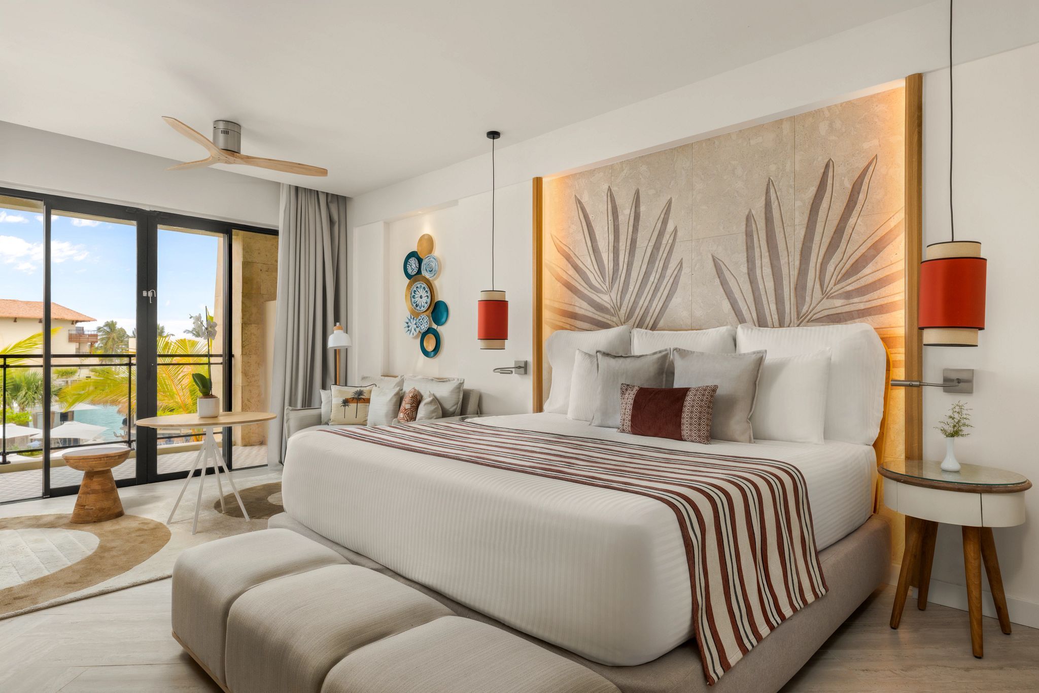 A modern bedroom with a large bed, a view of the outdoors, and a balcony.