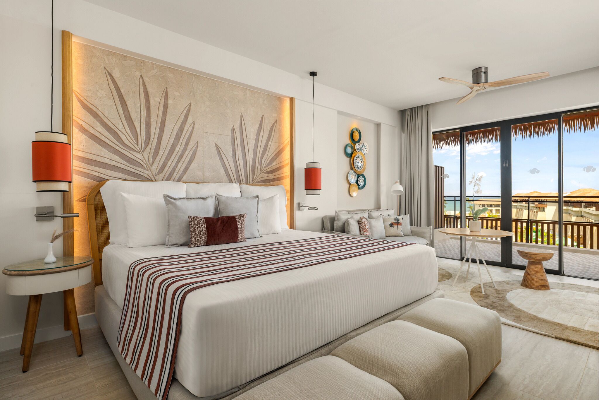 A modern hotel room with a large bed, a balcony with a view, and a ceiling fan.