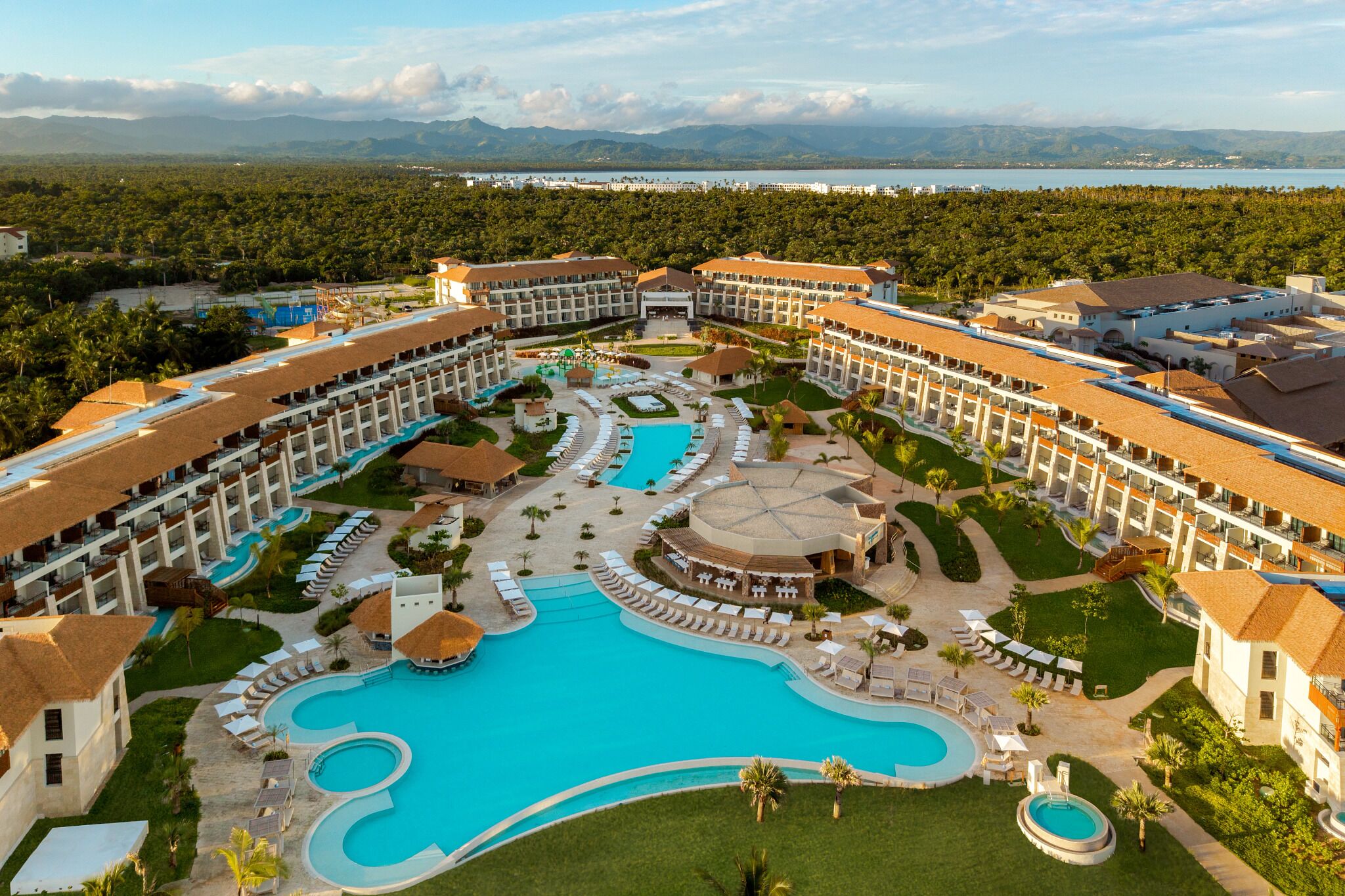 A resort with multiple swimming pools, a central courtyard, and a view of distant mountains.