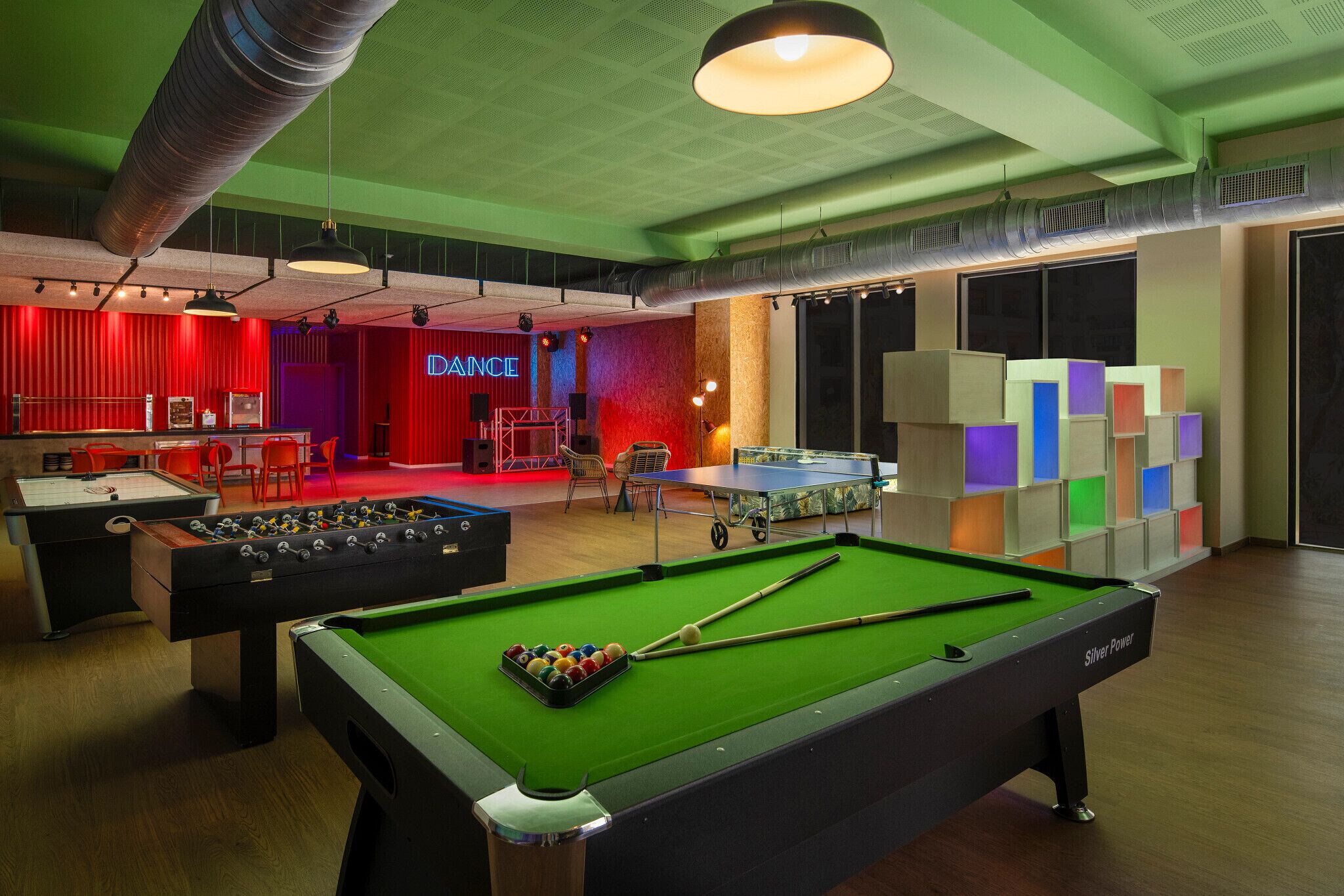 A billiards room with a pool table, foosball table, and a table tennis table.