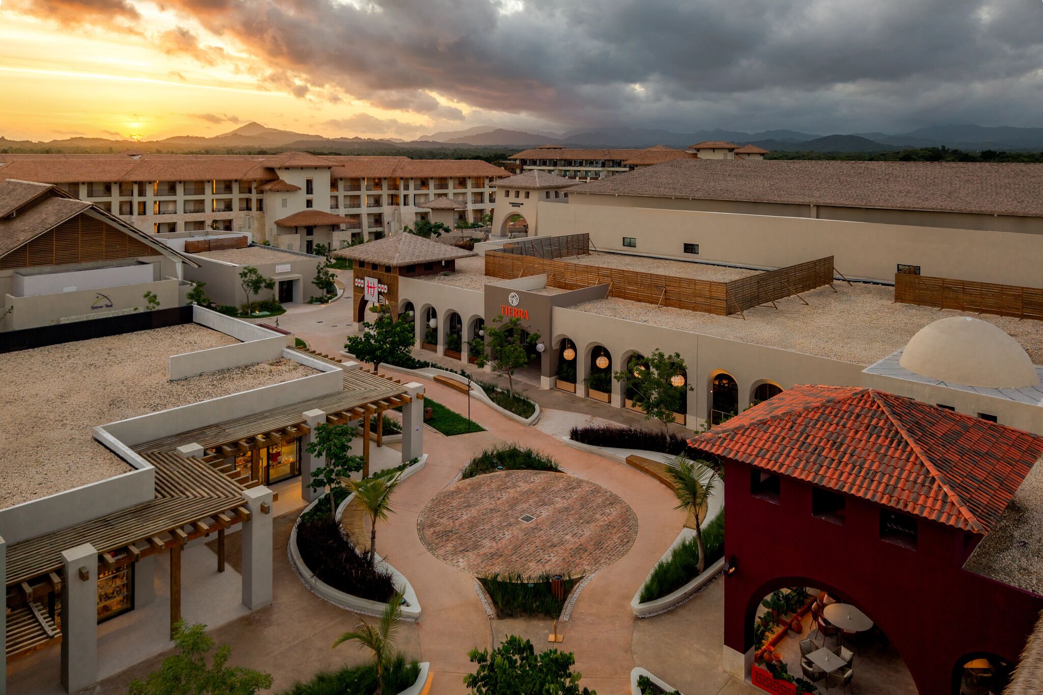A resort with multiple buildings, a central courtyard, and a view of distant mountains.