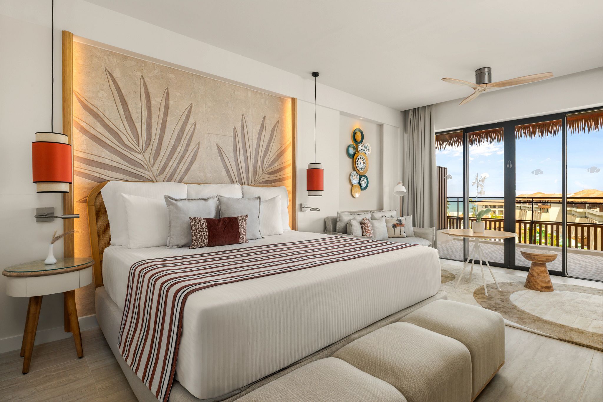 Une chambre d’hôtel moderne avec un grand lit, un balcon avec vue et un ventilateur de plafond.