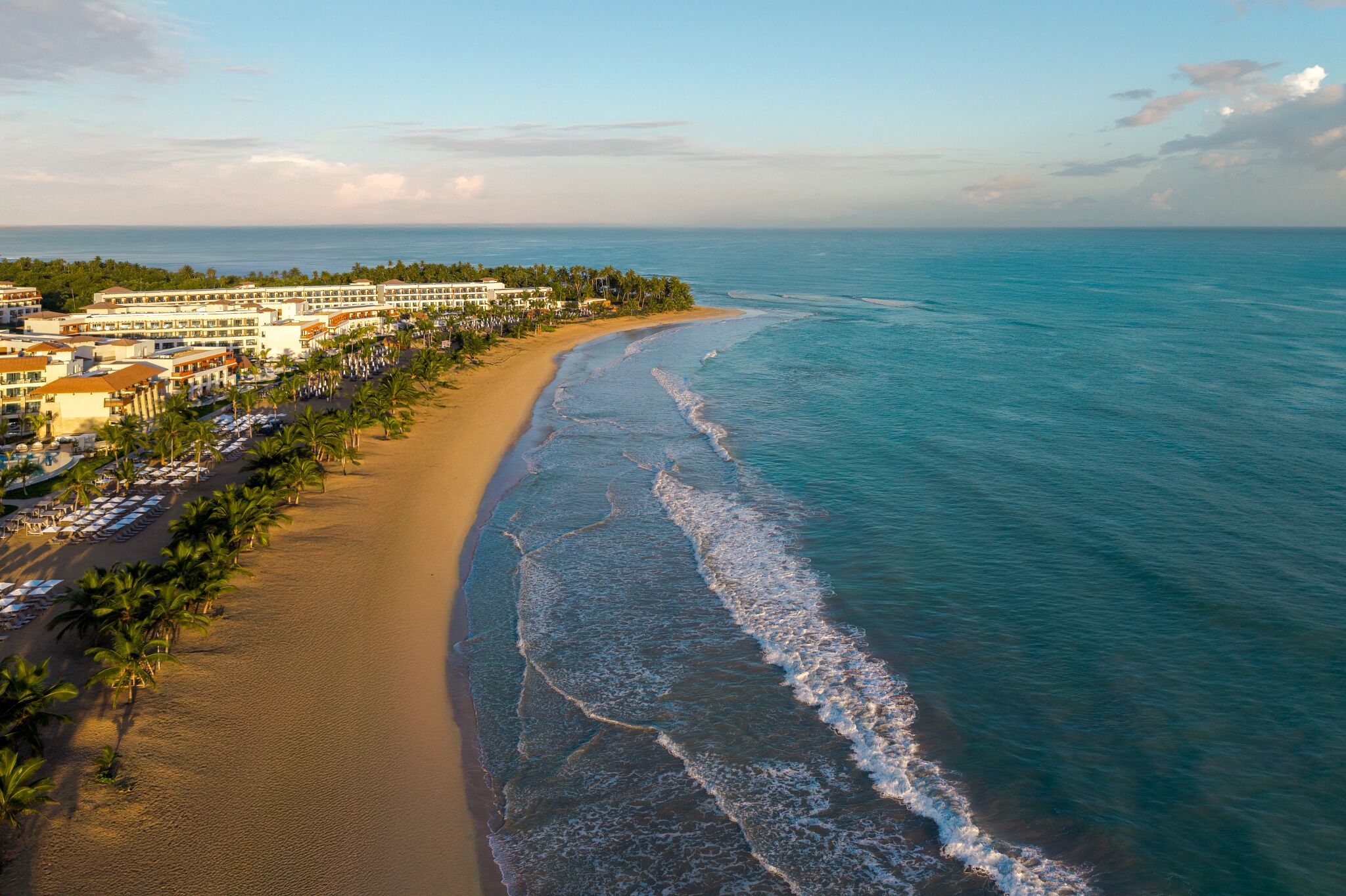 Ein Küstenhotel mit Blick auf den Strand, mehreren Gebäuden und einem langen Sandstrand.