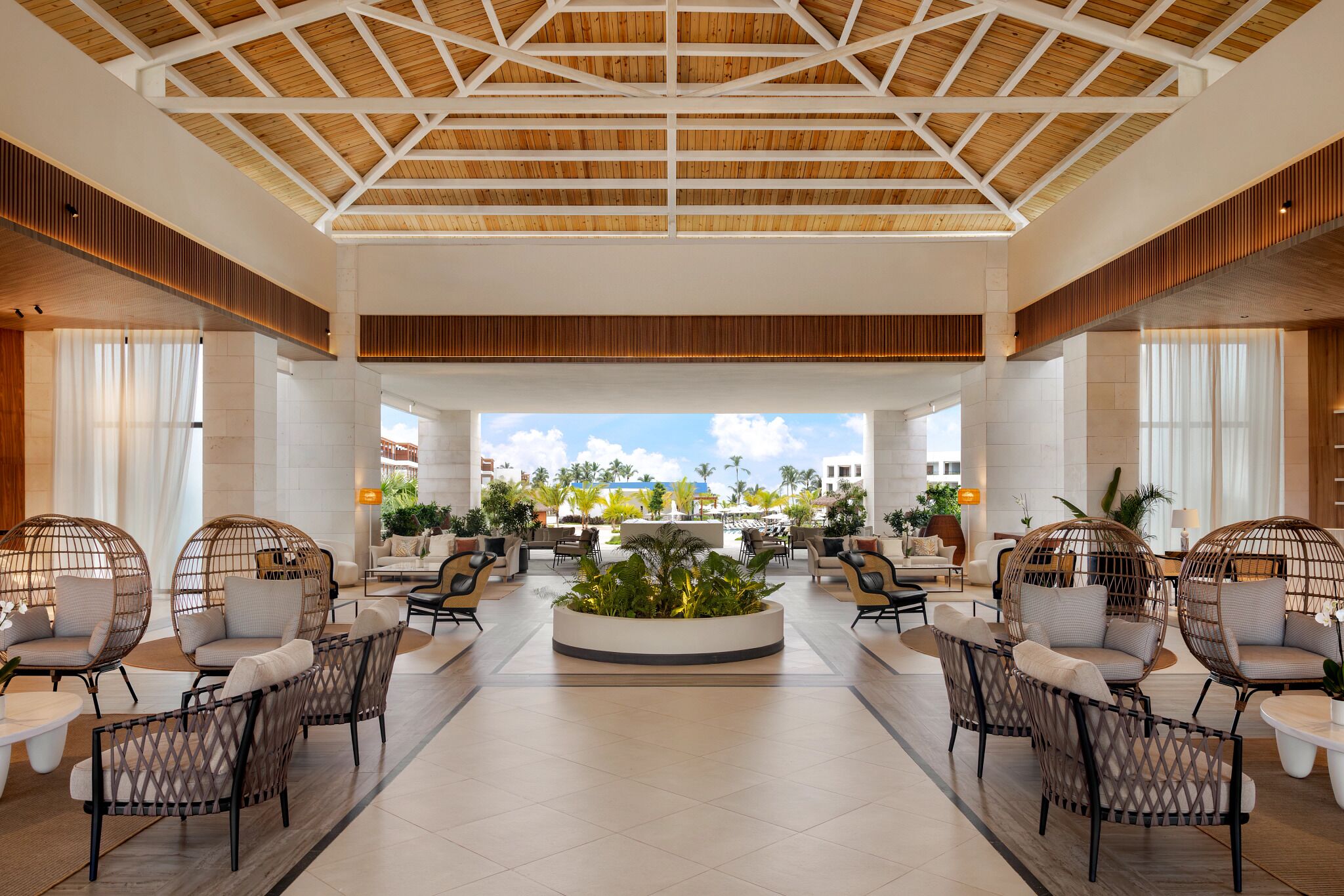 A spacious lobby with a high ceiling, modern furniture, and a central plant arrangement.
