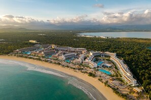 Une vue aérienne d’un complexe hôtelier comprenant plusieurs bâtiments, une plage et une vaste étendue d’eau.