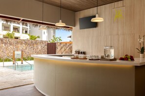 A modern reception area with a pool view, a stone wall, and a wooden ceiling.