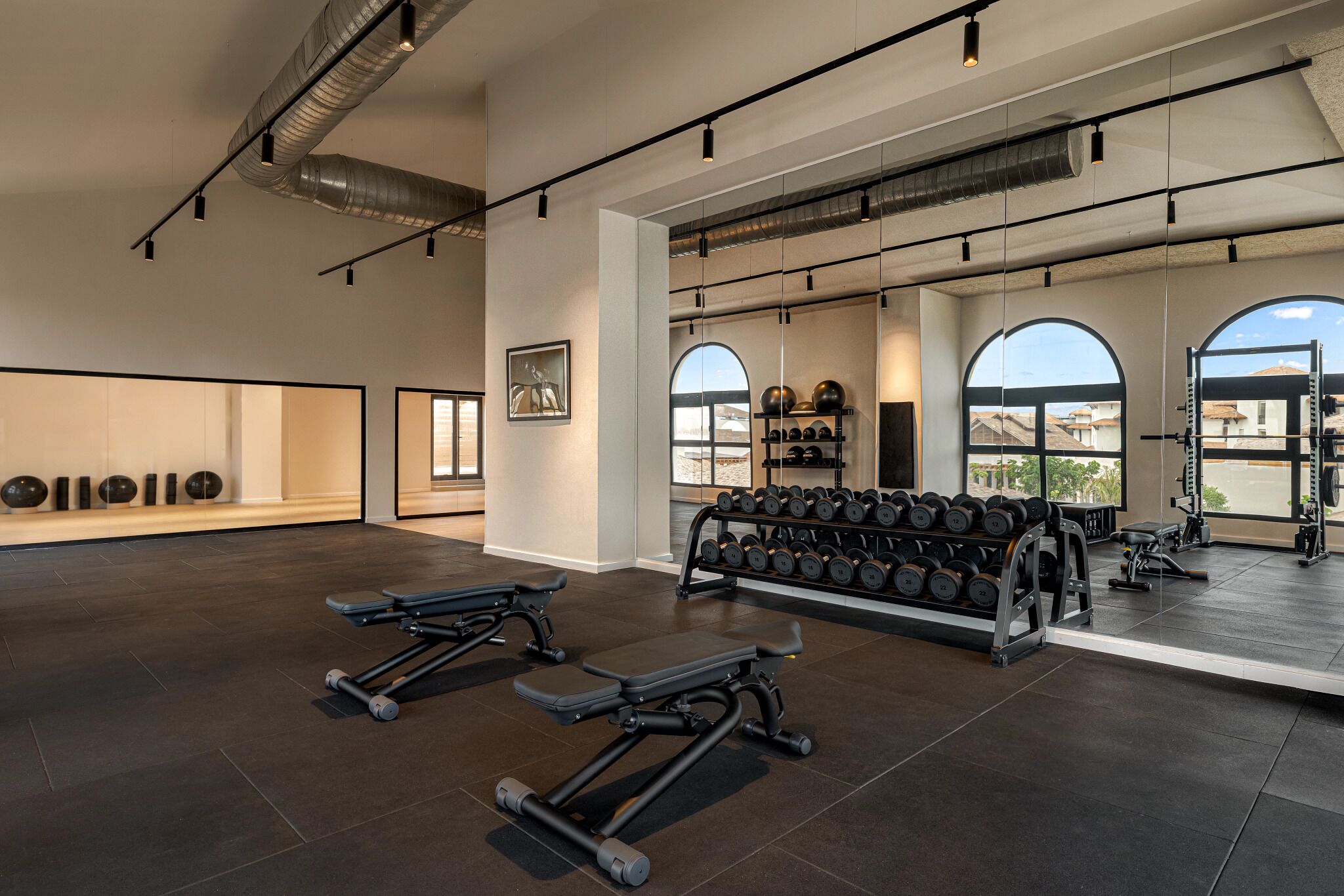 A gym with weightlifting equipment, dumbbells, and benches.