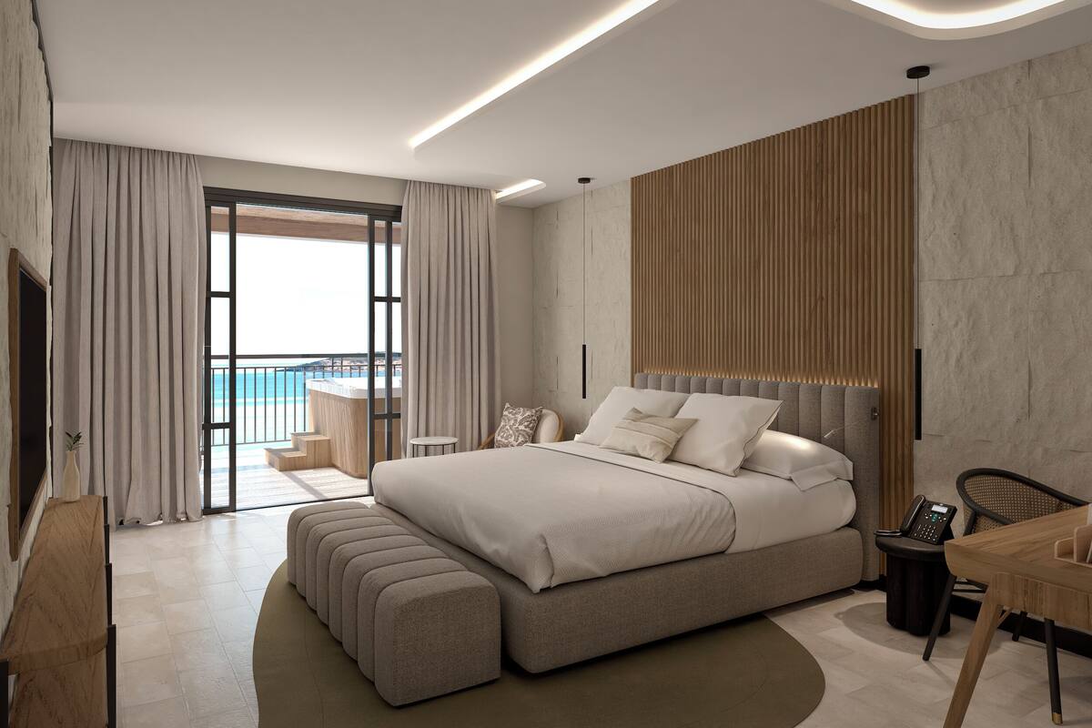 A modern bedroom with a large bed, a wooden headboard, a bedside table, and a view of the ocean.