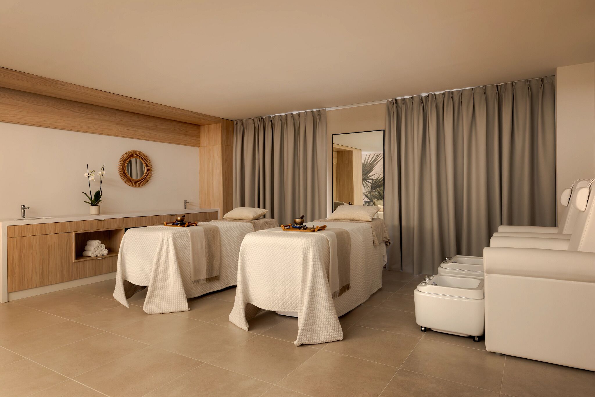 A modern hotel room with two beds, a sofa, a vanity, and a large mirror.