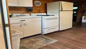A kitchen with white cabinets, a stove, and a refrigerator. - 2 Bedroom Riverside Cabin (The Forks)